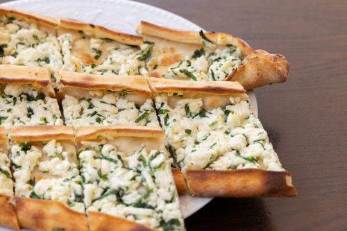 Free Close-up of a sliced cheese and herb flatbread, perfect for breakfast or snack. Stock Photo