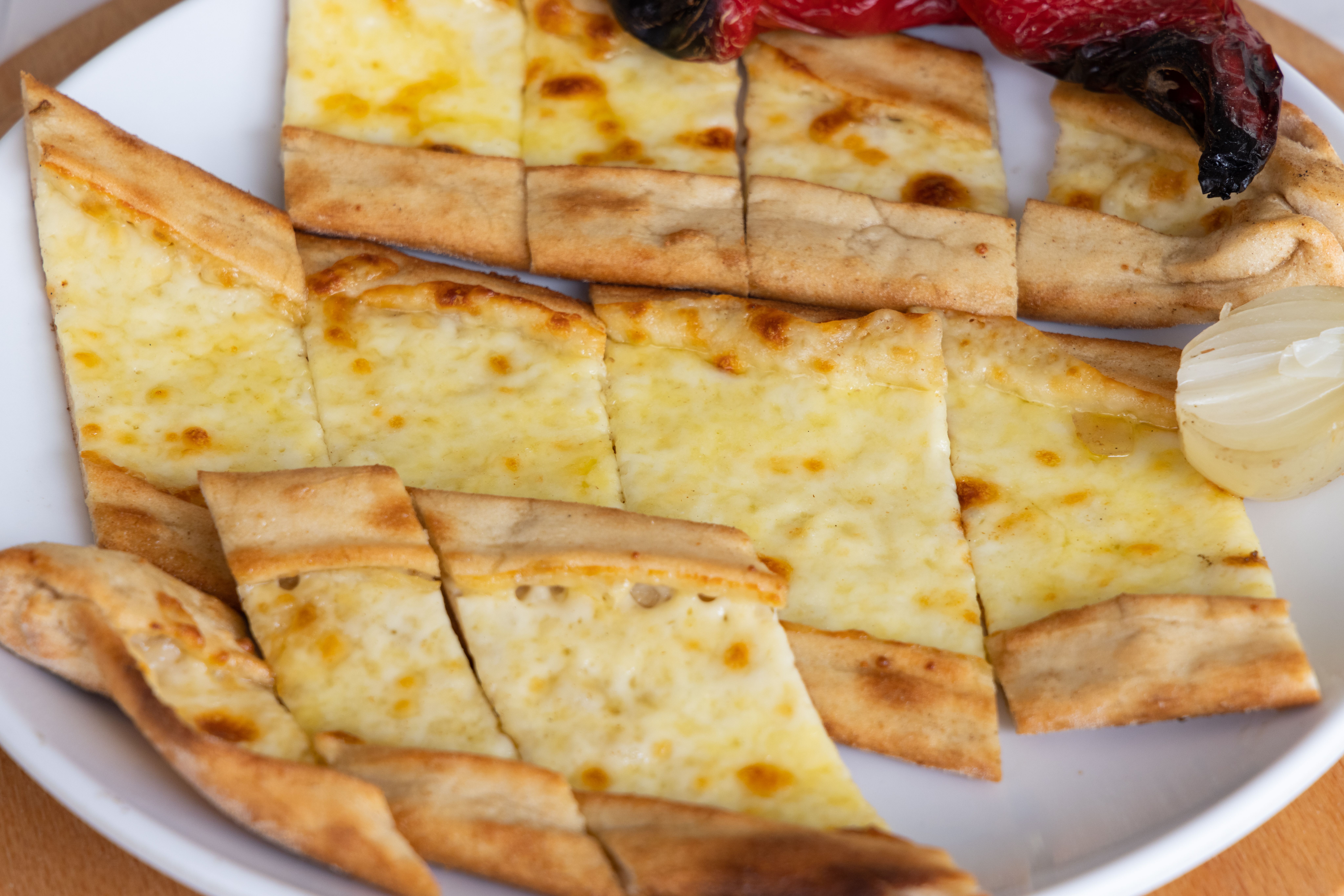 Sliced cheese pide on a plate with roasted vegetables, showcasing Turkish cuisine.