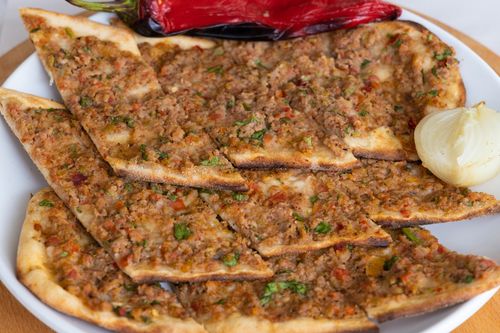 Free Close-up of traditional Turkish Lahmacun with fresh toppings on a white ceramic plate. Stock Photo