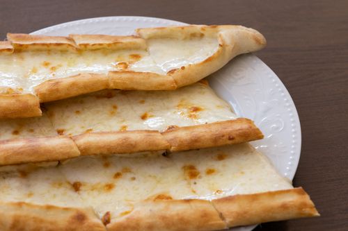 Free Delicious slices of Turkish cheese pide on a ceramic plate, perfect for food enthusiasts. Stock Photo