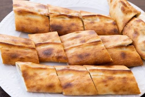 Free Appetizing close-up of golden toasted flatbread slices arranged on a white plate. Stock Photo