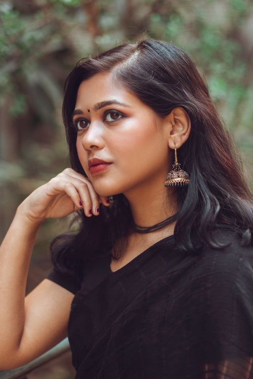 Free Elegant portrait of a South Asian woman in traditional attire with hand on chin, outdoors. Stock Photo
