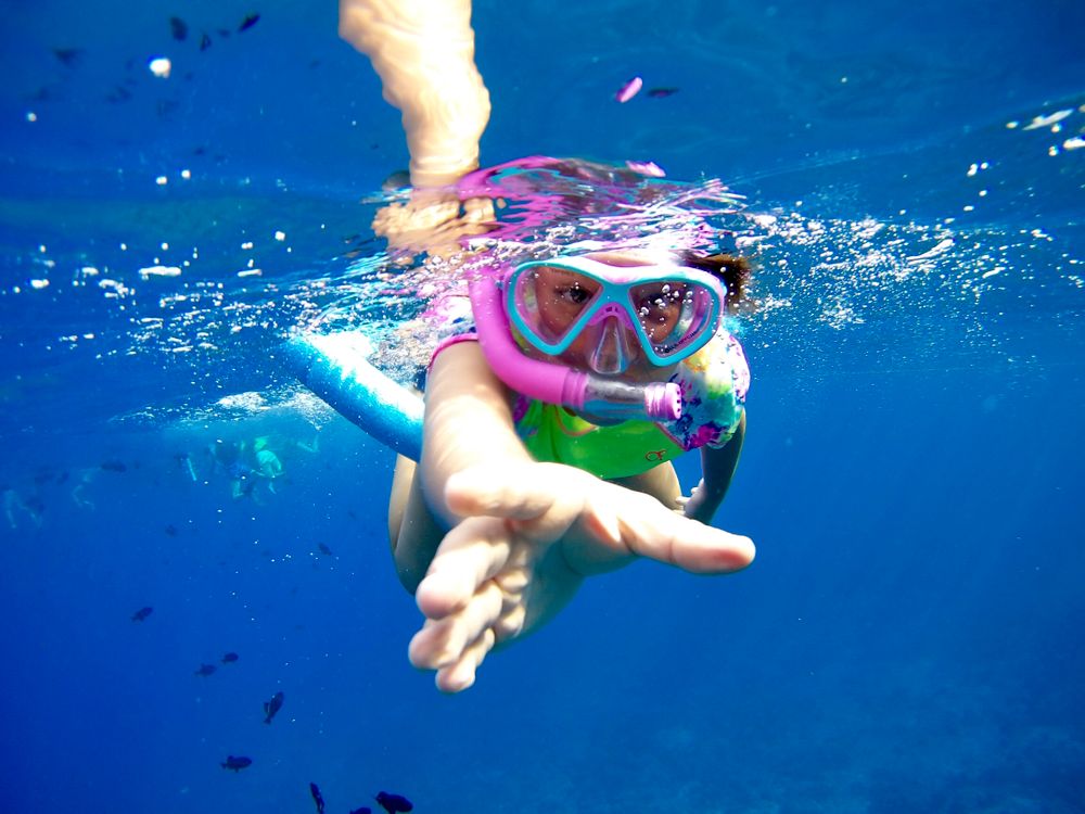 Kind schnorchelt im klaren Meer – bunte Fische sichtbar