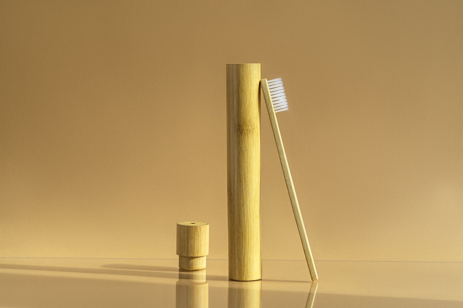 A bamboo toothbrush standing beside its case
