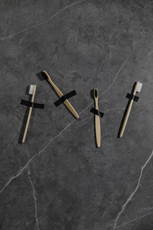 Free Minimalist composition of four bamboo toothbrushes taped to a dark marble surface, promoting sustainable dental care. Stock Photo
