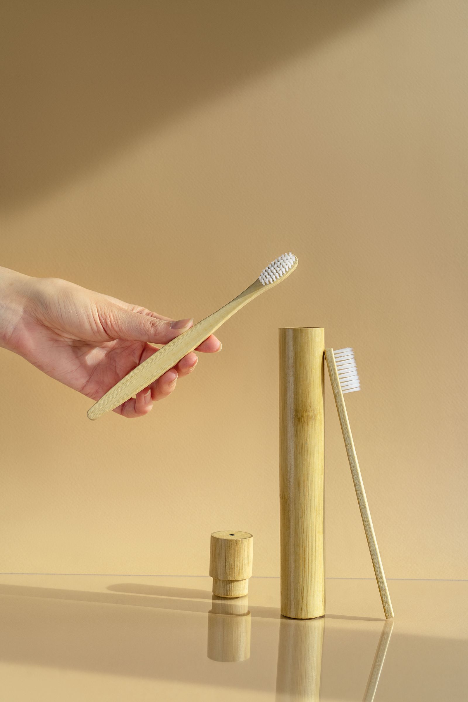 Bamboo toothbrush and oral care products on a beige surface — photo by Mikhail Nilov on Pexels