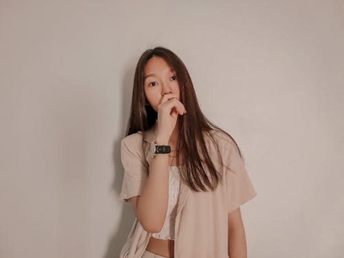 A Woman Leaning on a White Wall while Looking at the Camera