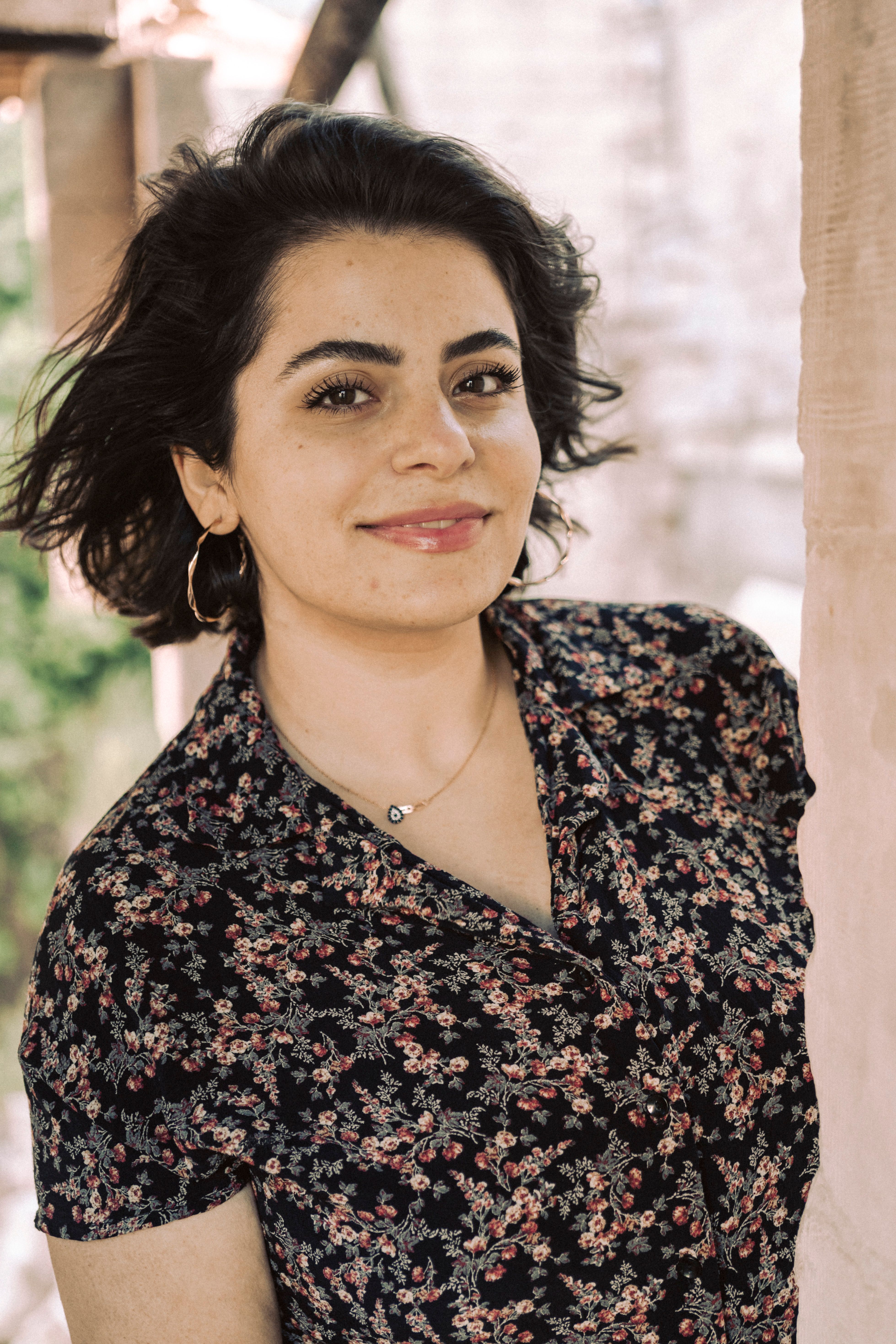 A cheerful woman in a floral blouse smiles warmly outdoors in Gaziantep, Turkey.