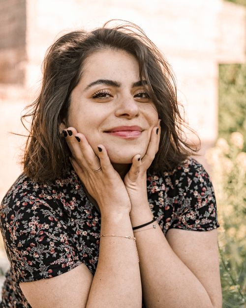 Free Portrait of a smiling woman in a floral dress enjoying the sunny day outdoors. Stock Photo
