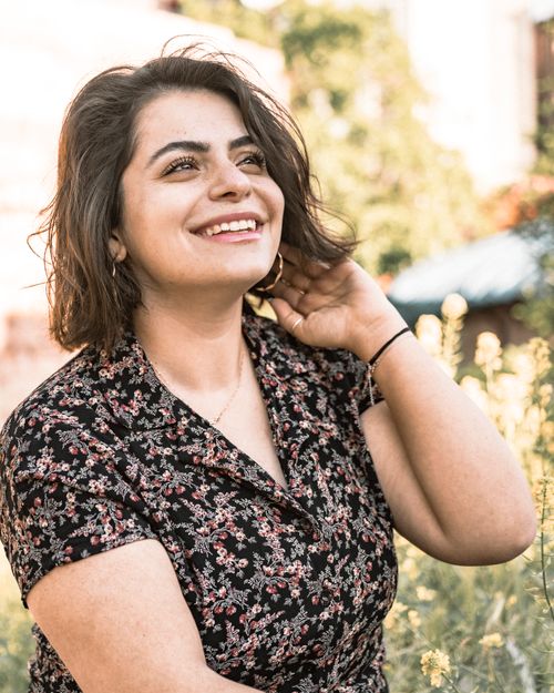 Free Portrait of a smiling woman in a floral shirt enjoying a sunny day outdoors. Stock Photo