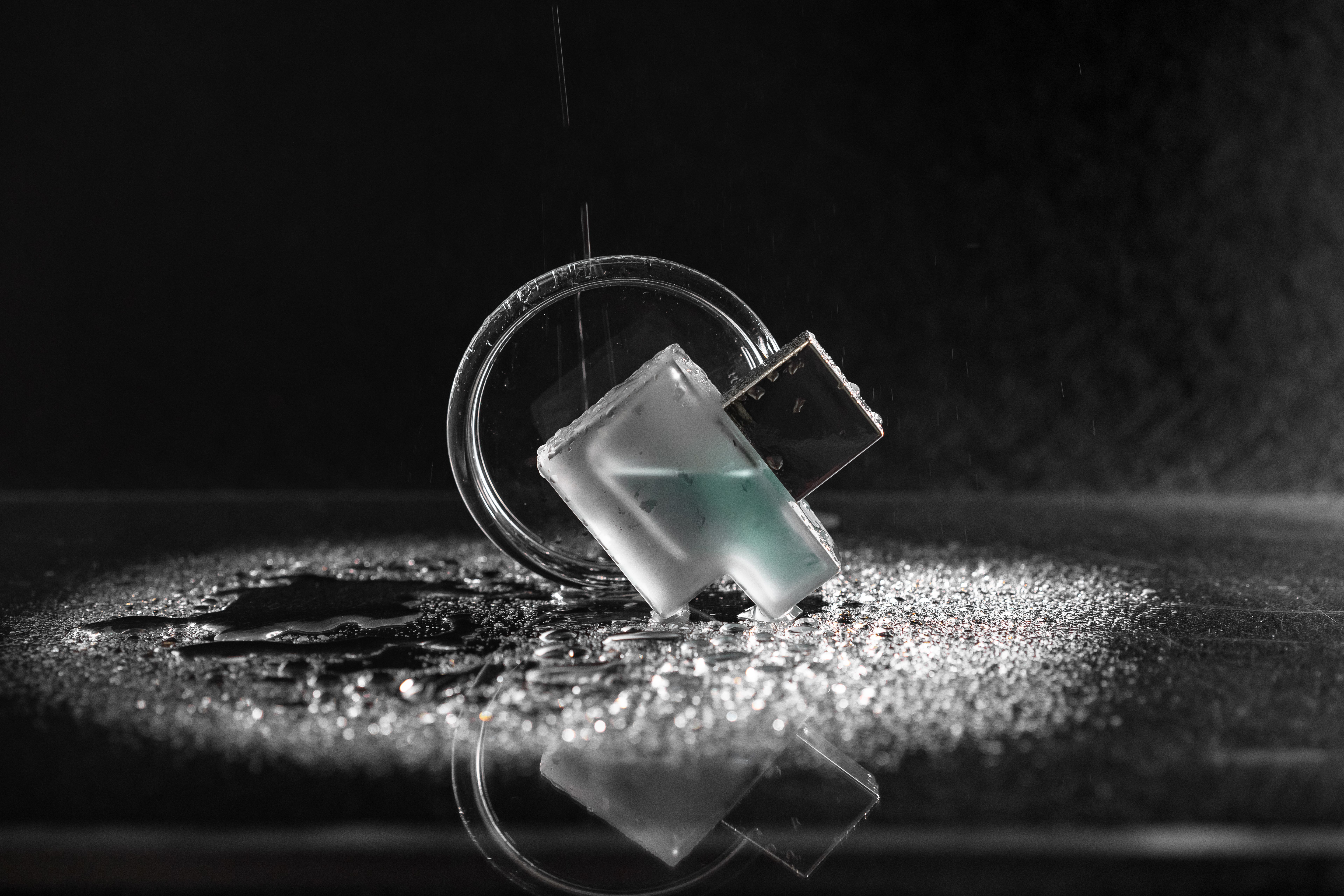 Minimalist close-up shot of a USB drive with water droplets on glass and dark background.