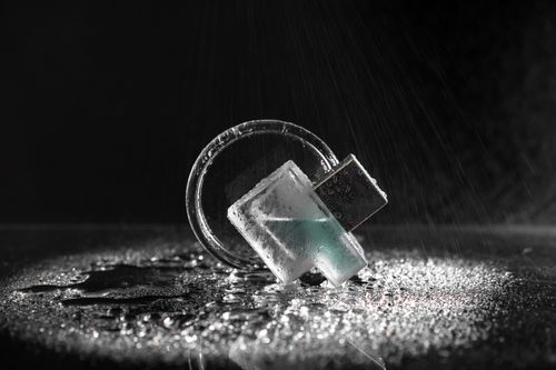 Free A close-up of a glass block with water droplets on a black background, highlighting texture. Stock Photo