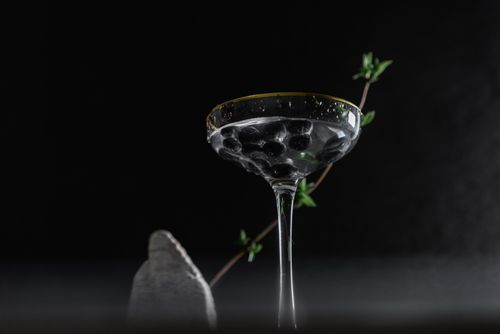 Free A sophisticated cocktail in a coupe glass with berries, set against a dark background. Perfect for a moody setting. Stock Photo