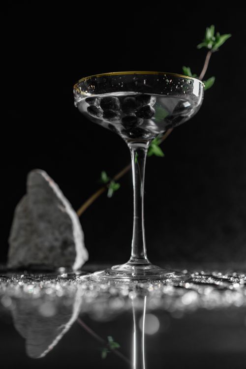 Free A sophisticated martini glass with olives on a reflective surface, perfect for elegant cocktail themes. Stock Photo