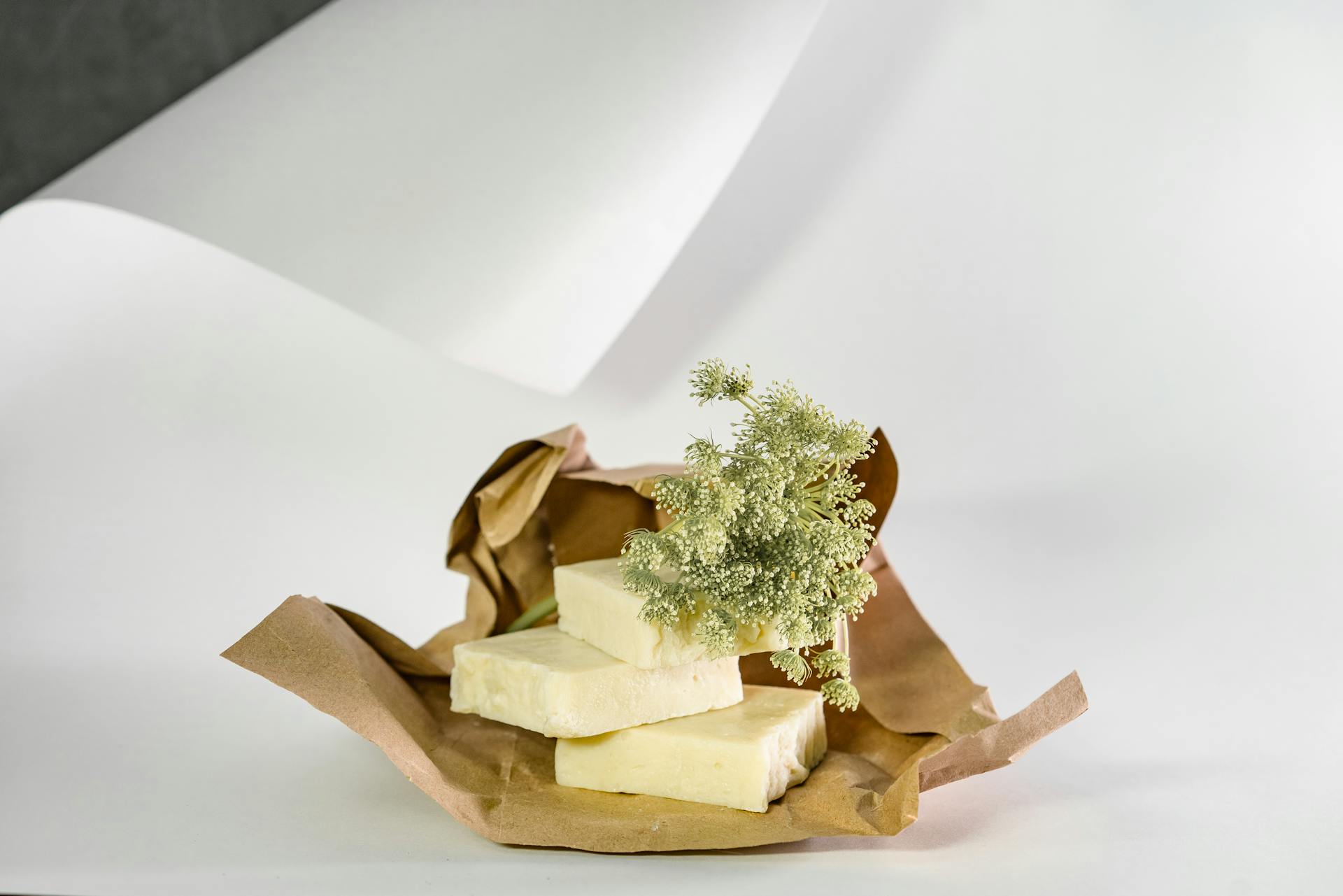 Aesthetic arrangement of natural soap bars with delicate white flowers on kraft paper and neutral background.