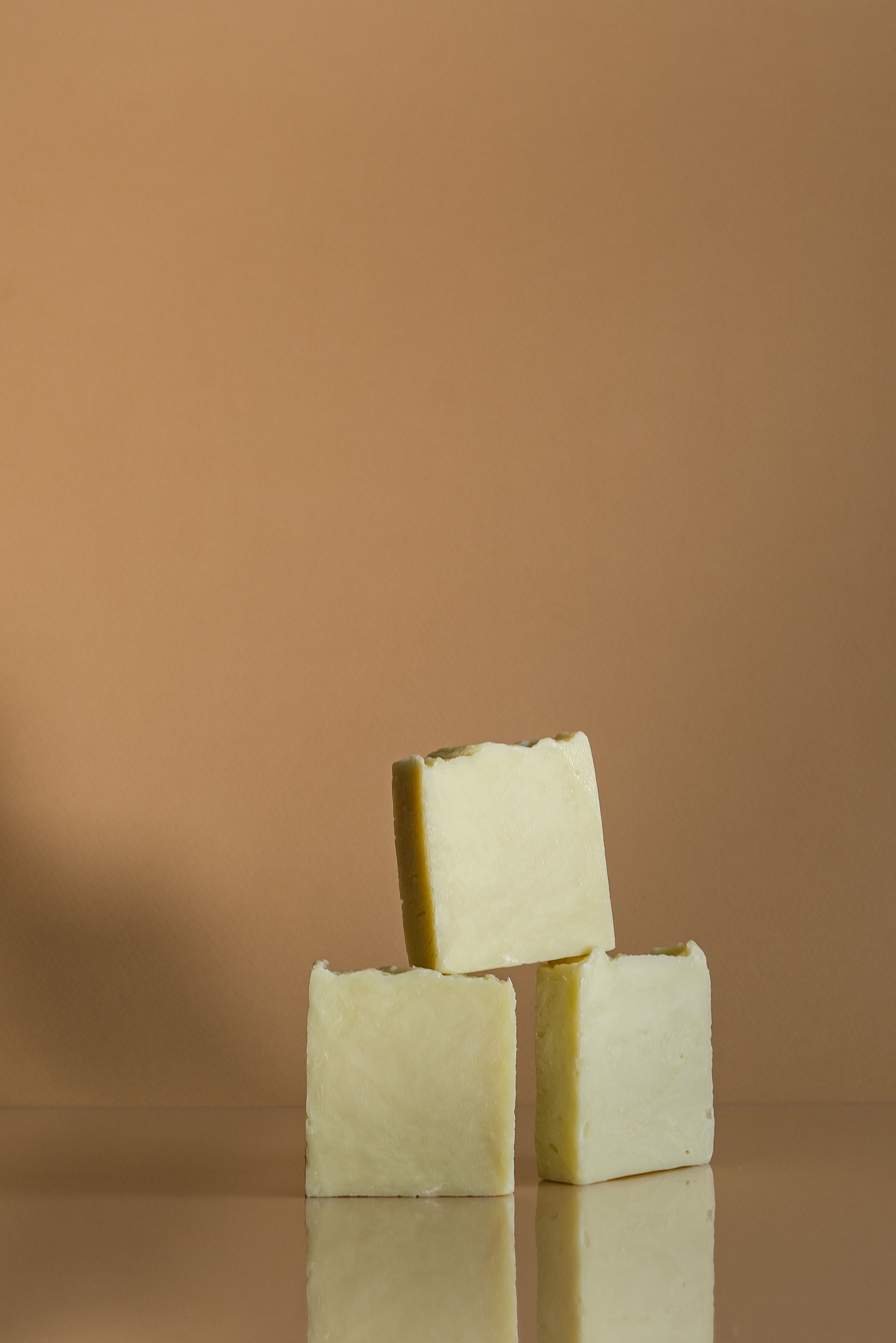Artistic display of natural soap blocks on a beige backdrop, emphasizing hygiene and minimalism.