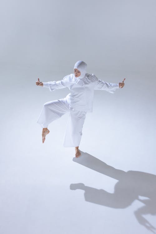 Person in White Long Sleeve Shirt and White Pants Dancing