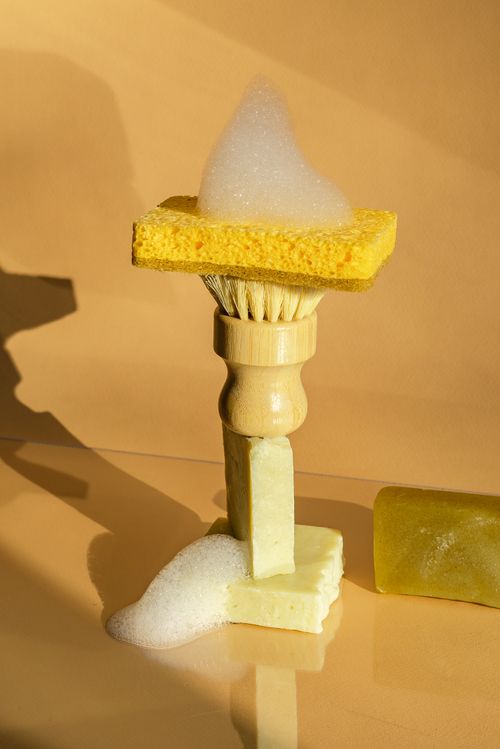 Free A still life composition of cleaning tools with soap and sponge on a bright yellow surface. Stock Photo