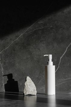 Minimalist skincare bottle with rock on dark marble background creating a modern aesthetic