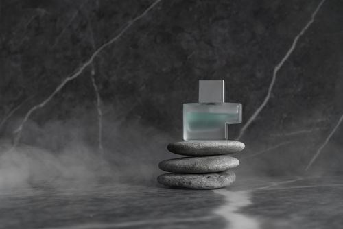 Free Perfume bottle placed elegantly on a stack of smooth stones with a marble backdrop. Stock Photo