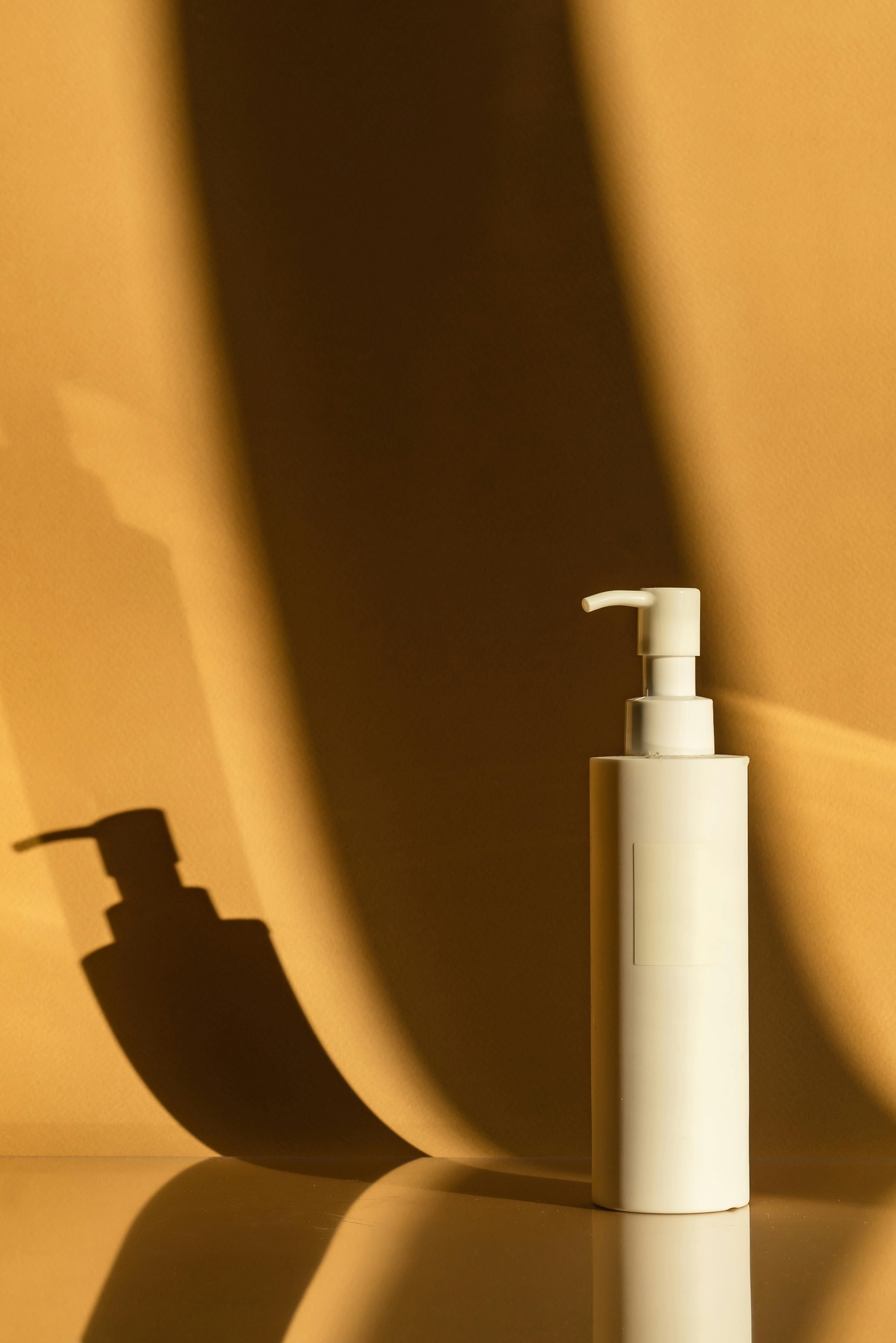 white plastic pump bottle with shadow on beige background