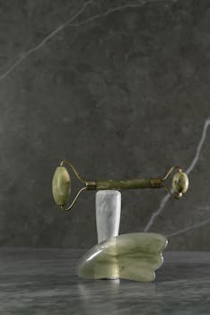 Stylish jade roller and gua sha set on marble surface for skincare routine.