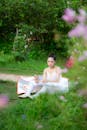 Serious Asian ballet dancer sitting on green grass