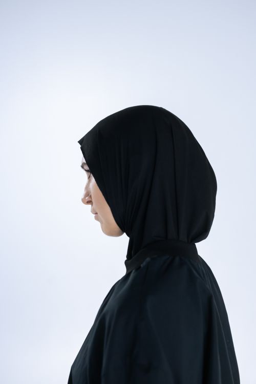 Free Side profile portrait of a woman wearing a black hijab against a white background, highlighting her serene expression. Stock Photo