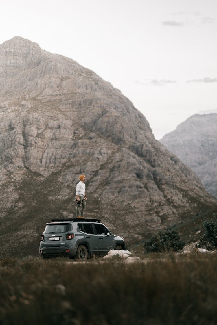 Man Standing On Top Of A Parked Car