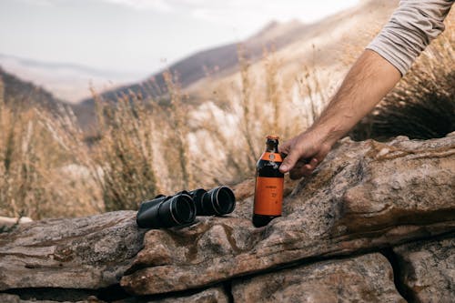 Free Photo of Black Binoculars Beside a Bottle of Beer Stock Photo