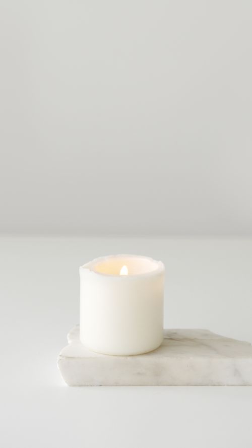 Free Elegant lit white candle on a marble slab creating a minimalist and tranquil setting. Stock Photo
