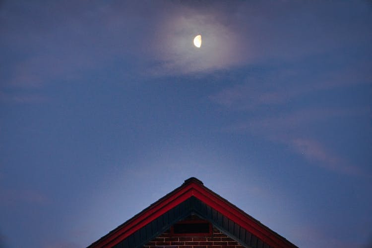 A Moon In The Blue Sky Over The Roof Of The House