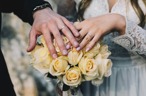 Free Photo of Hands with Rings on a Bouquet of Yellow Roses Stock Photo