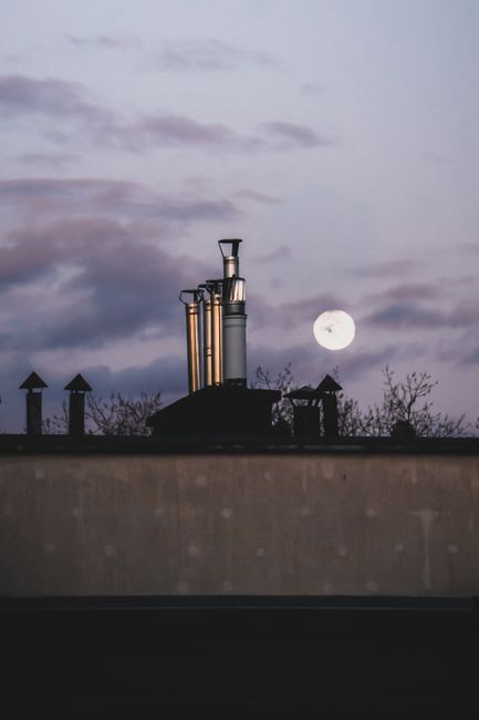 Scenic view of Torun rooftop featuring chimneys against a twilight sky with the moon.