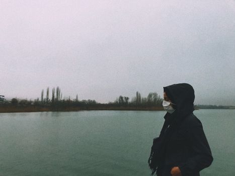 A person wearing a mask stands by a lake in Gölbaşı, Turkey, reflecting the new normal.