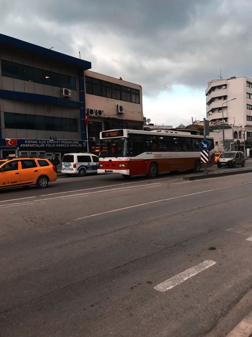 Free Busy urban street with public bus and cars in front of office buildings under cloudy sky. Stock Photo