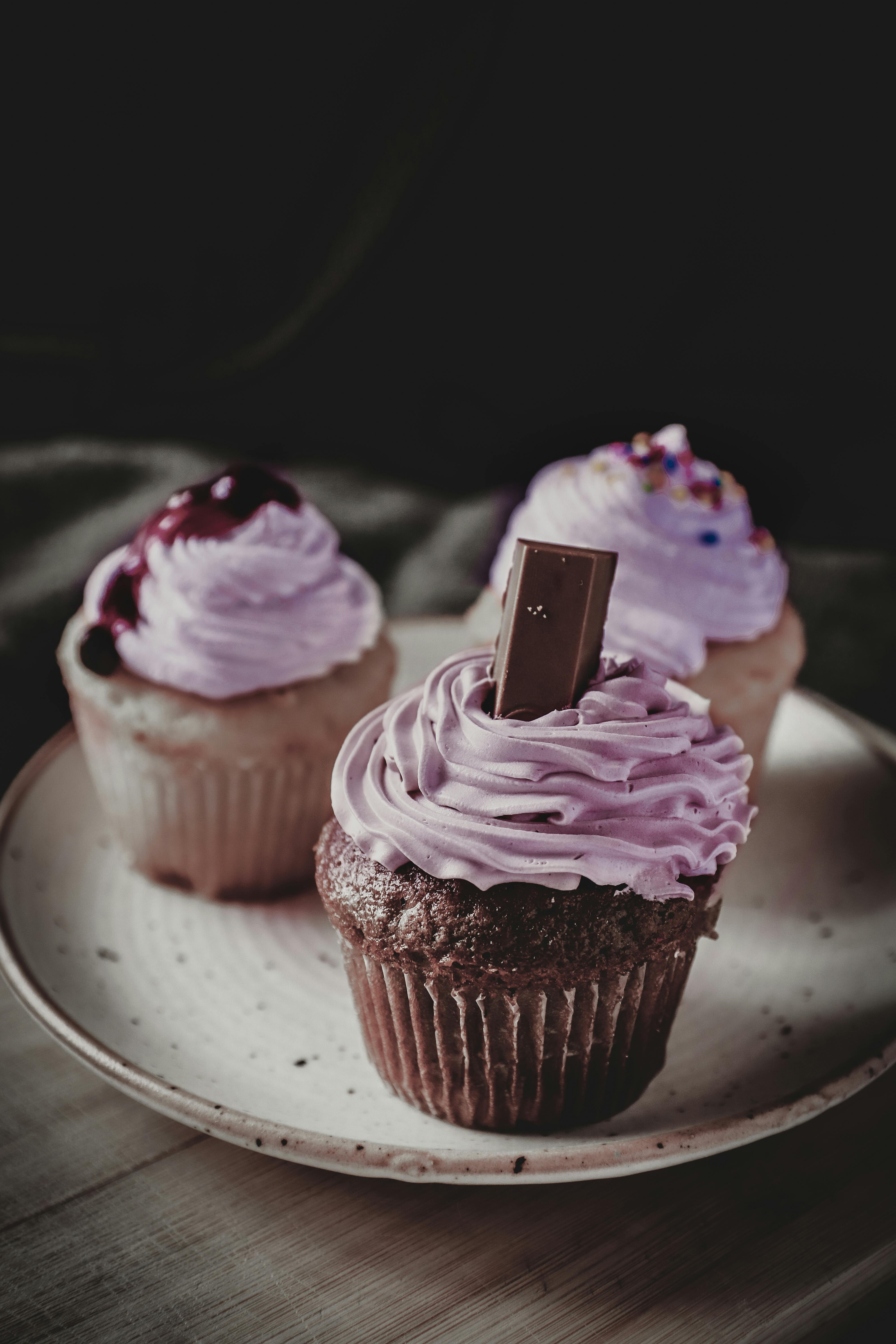 High angle of sweet homemade cupcakes decorated with berries and chocolate topping served on plate