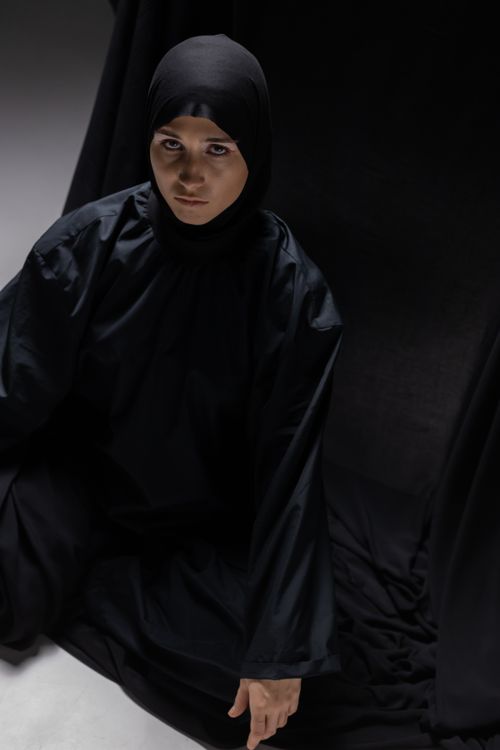 Free A woman in traditional black attire poses indoors with dramatic lighting. Stock Photo