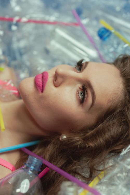 Free Model surrounded by plastic bottles and straws emphasizing pollution issues. Stock Photo