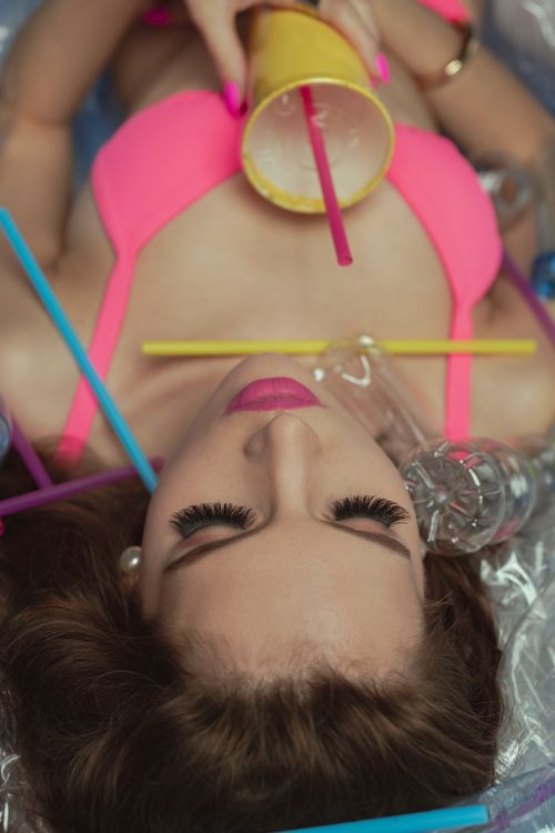 Free Portrait of a woman surrounded by plastic bottles highlighting pollution issues. Stock Photo
