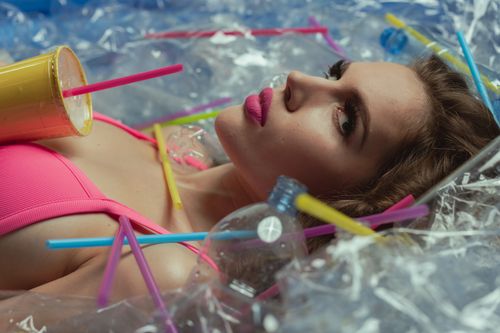 Free Woman amidst plastic waste raises awareness on ocean pollution. Stock Photo