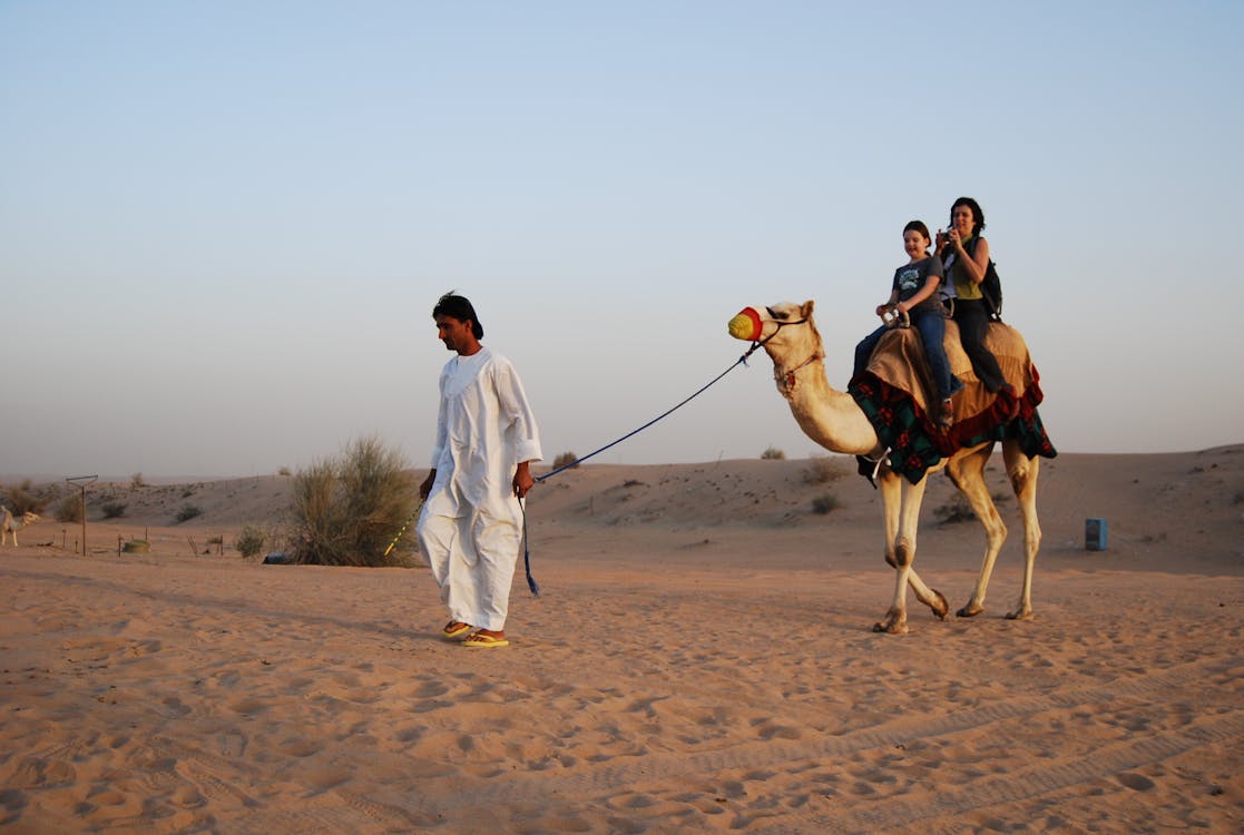 Man in white thobe walking on brown sand