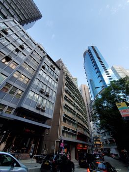 Low angle photo of a bustling city street surrounded by high-rise buildings and blue sky.