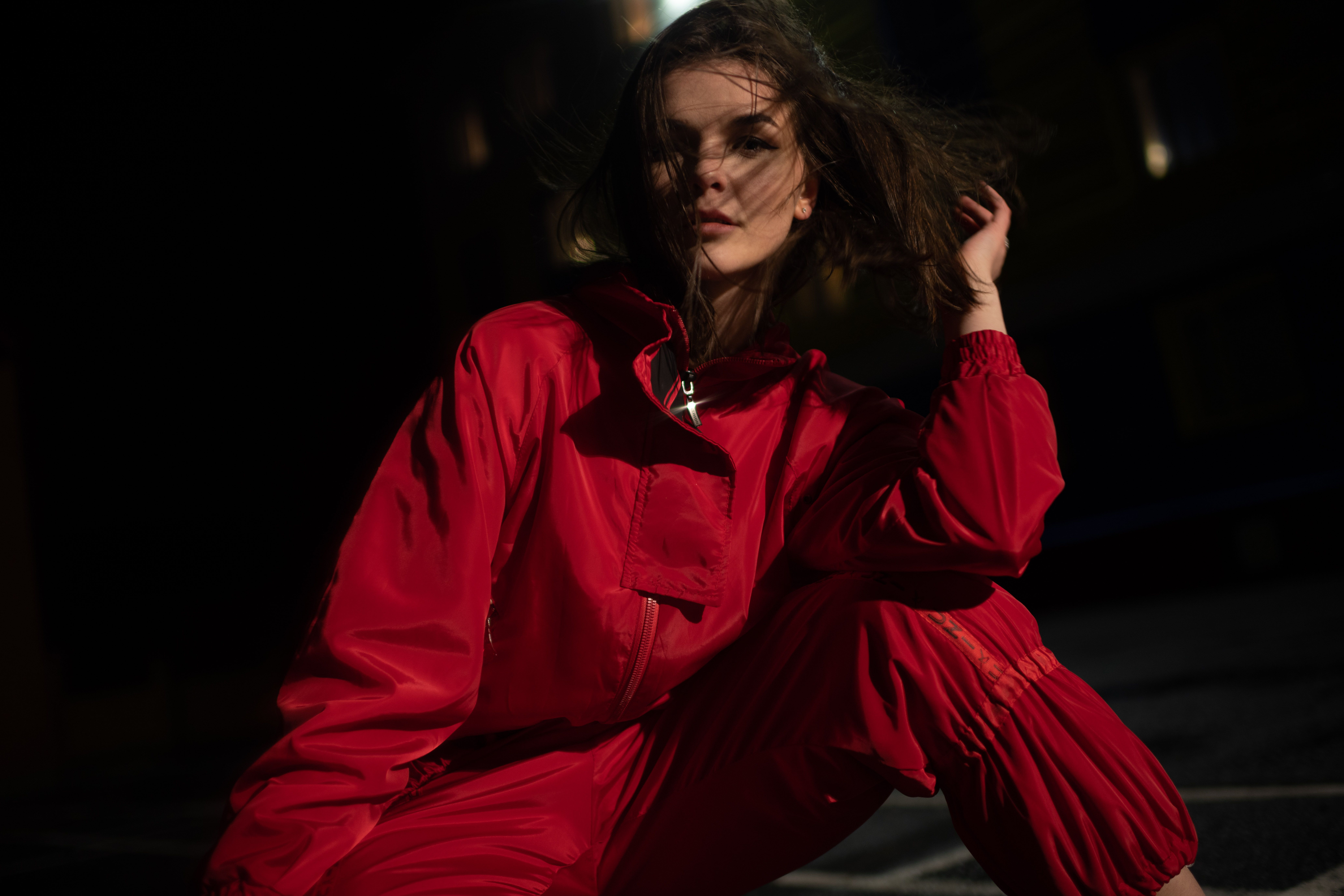 Caucasian woman striking a pose in red attire, captured at night.
