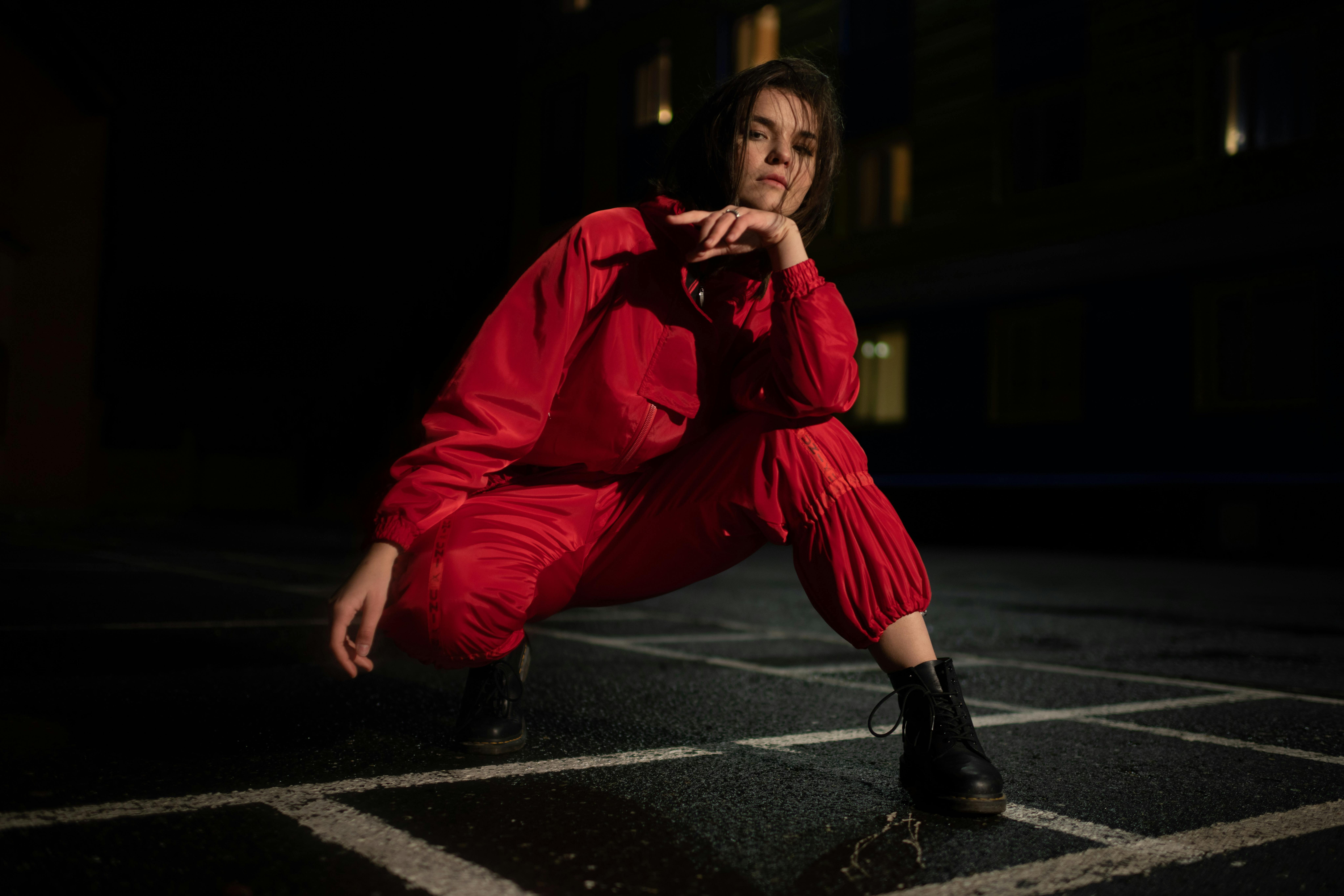 Free Stylish woman posing in a vibrant red outfit at night, evoking a bold and moody atmosphere. Stock Photo