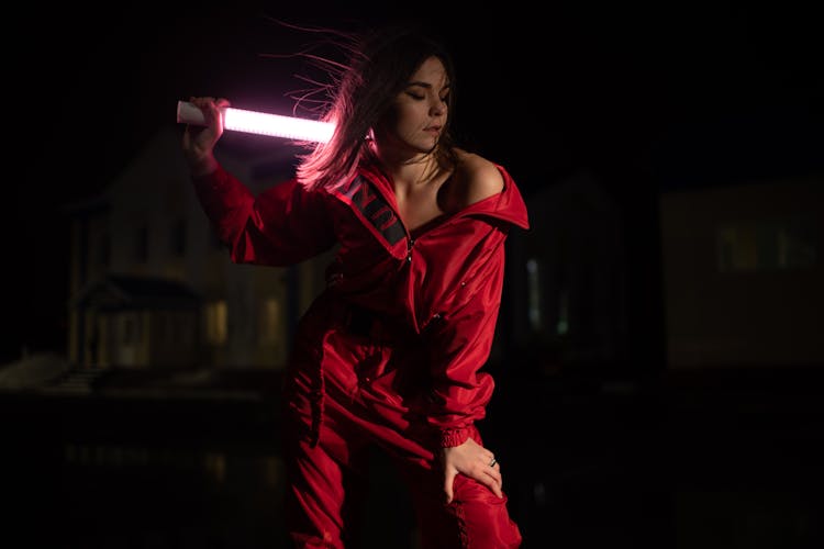 Woman In Red Jumpsuit Holding Tube Light