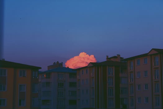 Silhouette of apartment buildings with a vibrant sunset sky and clouds.