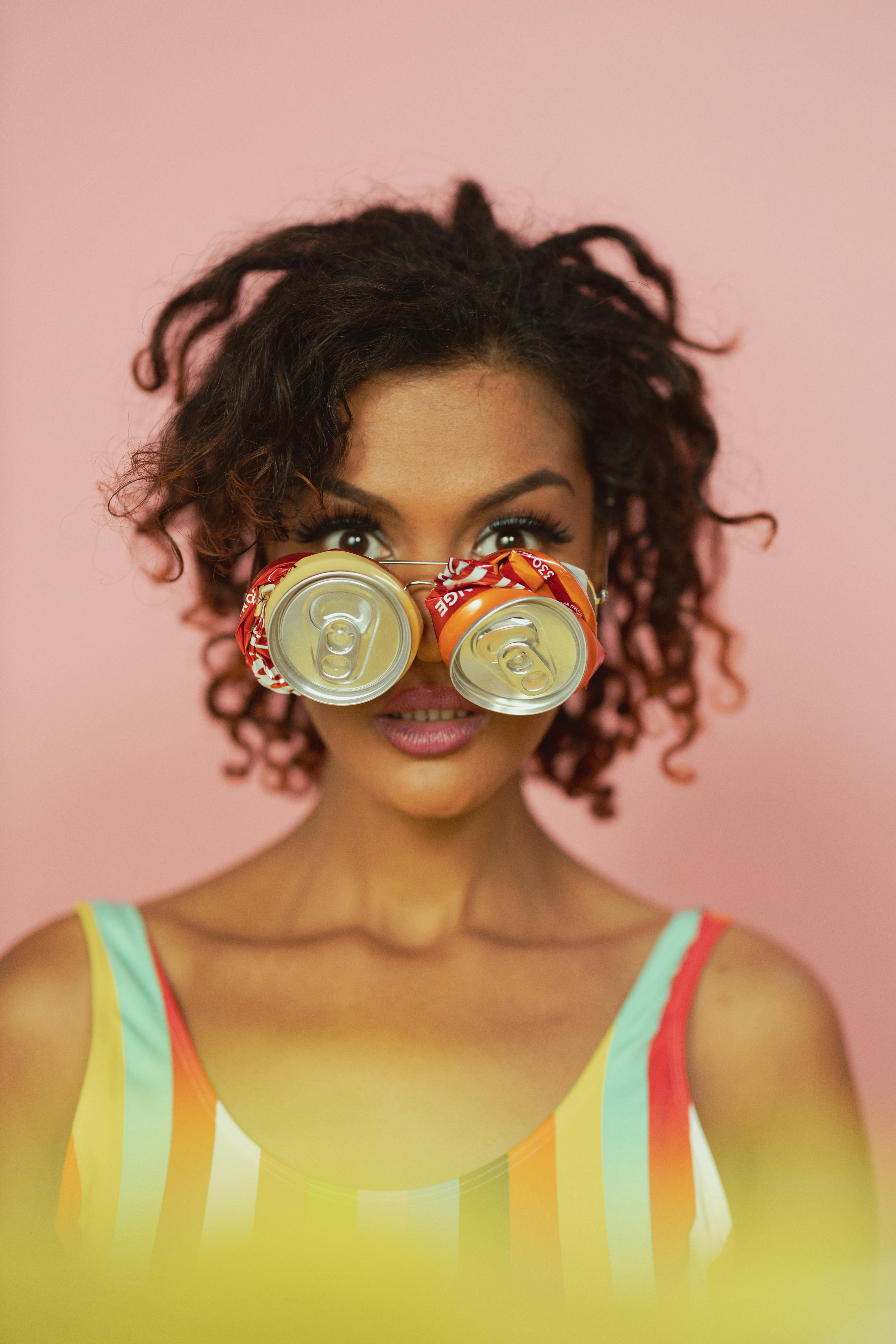 Colorful portrait of a woman wearing recycled can eyewear against a pink backdrop.