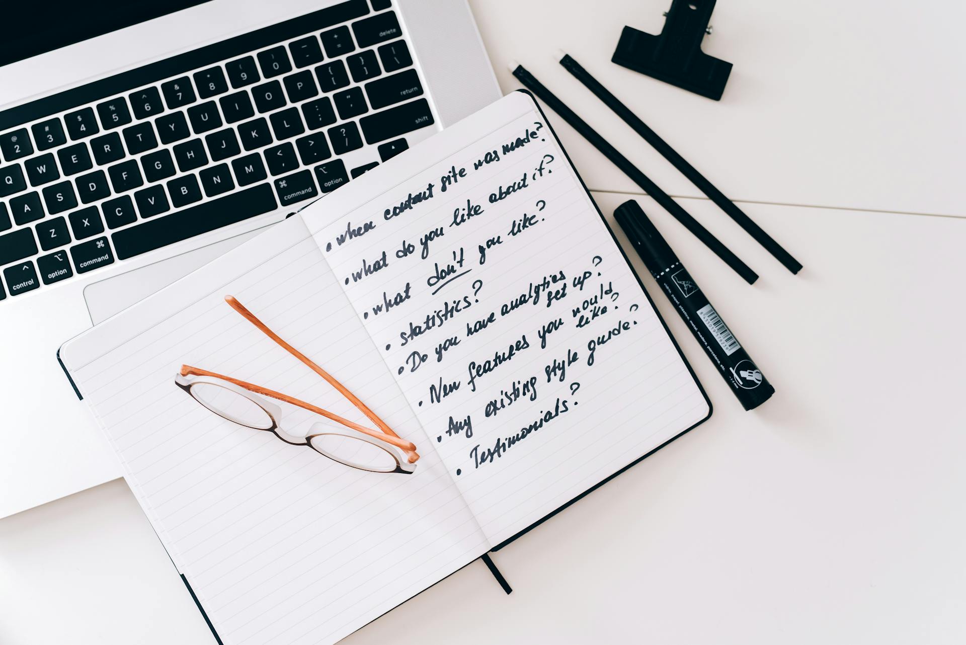 An Open Notebook with Notes Beside a Laptop