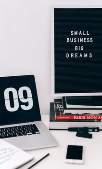Modern workspace featuring a laptop, smartphone, and motivational quote board.